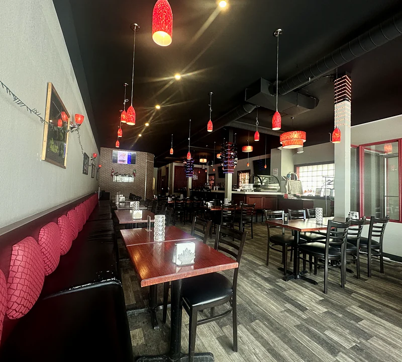 The dining room at Saffron with red booth seating and red glass pendant lights