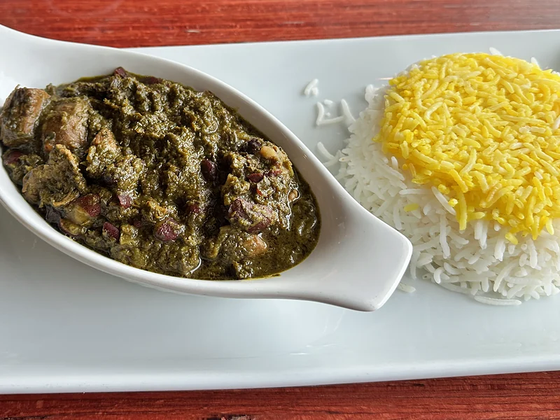 Khoresh ghormeh: herb stew with beef and kidney beans beside saffron rice and pickles